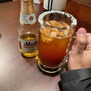 a person&apos;s hand holding a glass of tequila