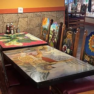 Painted chair backs and table tops have authentic artwork.