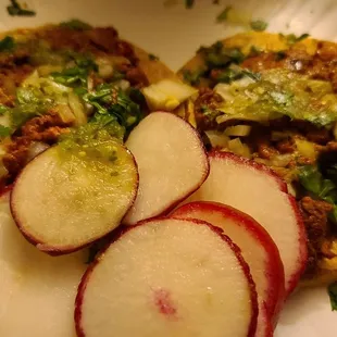 a plate of tacos and sliced radishes
