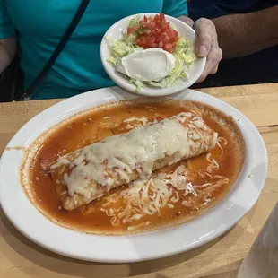 Chicken burrito Al a carte with side of lettuce , tomato, sour cream