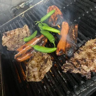 steaks and hot dogs on a grill