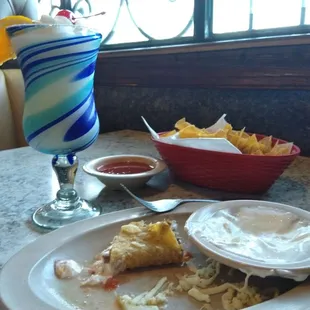 My mostly eaten taco with sour cream, a pina colada, and tortilla chips &amp; salsa.