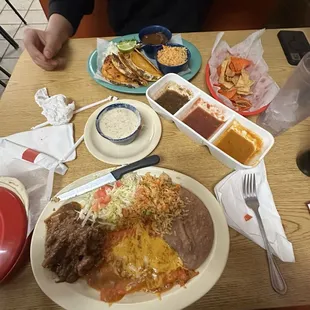 Quesabirria Tacos (blue plate) Carne guisada and cheese enchiladas (white plate)
