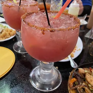 a close up of two margaritas on a table