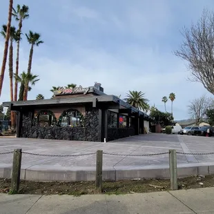 a small restaurant with palm trees in the background