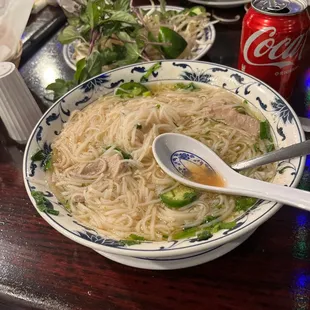 a bowl of noodles and a can of coke