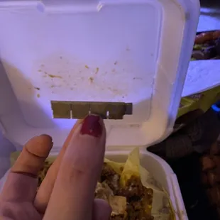 a hand holding a container of food