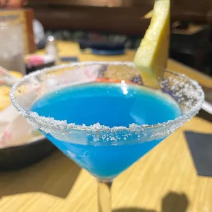 a blue cocktail in a martini glass