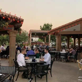 people sitting at tables outside a restaurant