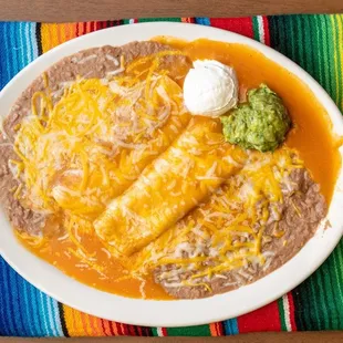 Enchiladas Rancheras with rice bean, and a side of sour cream.