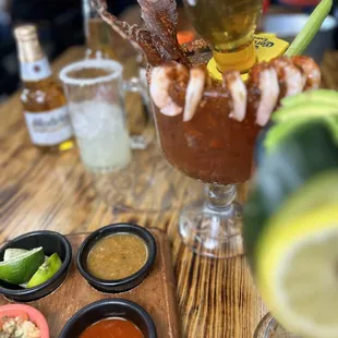 a bloody cocktail with shrimp, lime, and other condiments