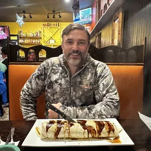 a man sitting at a table with a plate of food