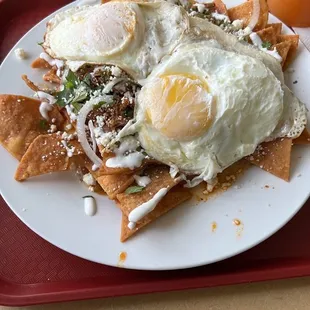 Steak Chilaquiles, refried beans with 2 over easy eggs.