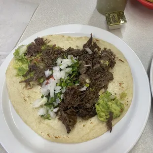 Barbacoa taco with guacamole, onion &amp; cilantro.