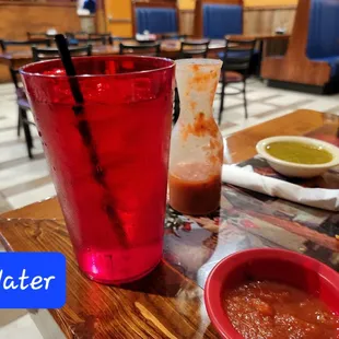 a red drink and a bowl of salsa