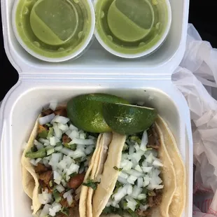 Al pastor (left) and carne asada (right) tacos with 2 limes and 2 to-go containers of salsa verde ($4.06)