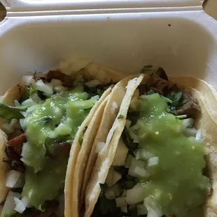 Al pastor (left) and carne asada (right) corn tortilla tacos with onions and cilantro topped off with salsa verde