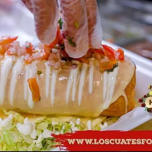 a person putting toppings on a sandwich