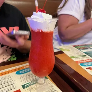a child sitting at a table with a drink