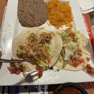 Two chicken soft tacos, refried beans and rice