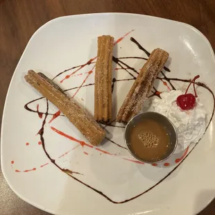 a plate of churros and a cup of coffee