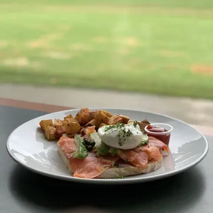 Open face , smoked salmon scallions avocado capers cream cheese on sourdough with poached egg and potatoes