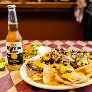 a plate of nachos and a bottle of corona beer