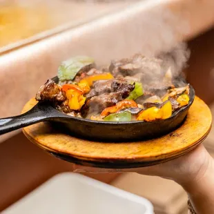a person holding a frying pan of food