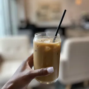 a hand holding a glass of iced coffee