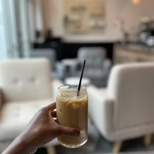 a hand holding a glass of iced coffee