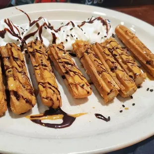 Amazing churros drizzled with chocolate and apple caramel with whip cream