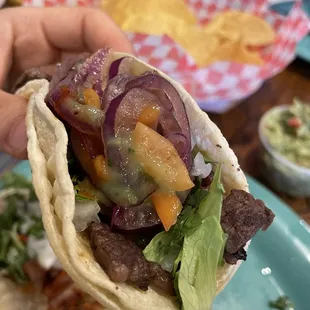 Steak taco with onions, peppers, and sauce