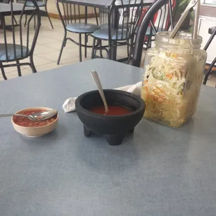 a table with a bowl of soup and a jar of sauce