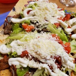 a plate of nachos topped with cheese and lettuce