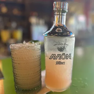 a bottle of avon vodka next to a glass