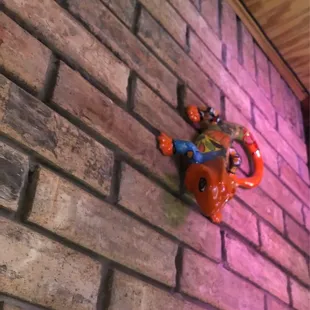 a ceramic frog on a brick wall