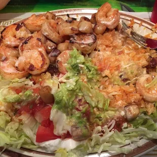 Arroz Con Mariscos - grilled shrimp and scallops over mexican rice, with nacho cheese. Combined with guac, lettuce, and tomato