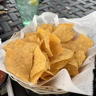 a basket of nachos and a glass of water