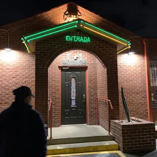 The green entrance sign on the side of the building opposite the driveway