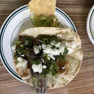 One beef fajita taco on flour, minus lettuce and tomato due to spouse's preference.