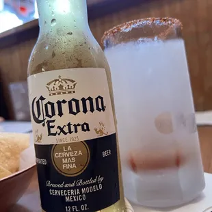 a bottle of corona extra next to a glass of beer