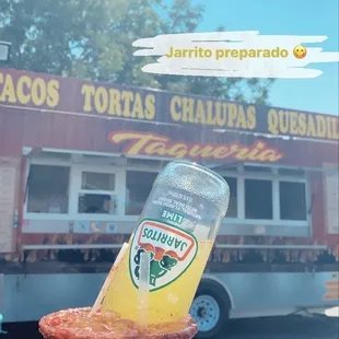 a person holding a drink in front of a food truck