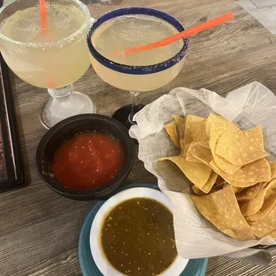 a table with drinks, chips and salsa