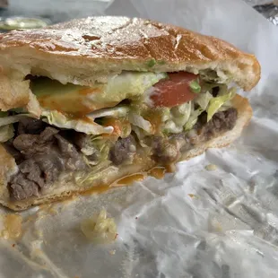 Torta de Asada includes mayo, lettuce, tomato, bean spread, avocado, chopped up streak, and telera bread.