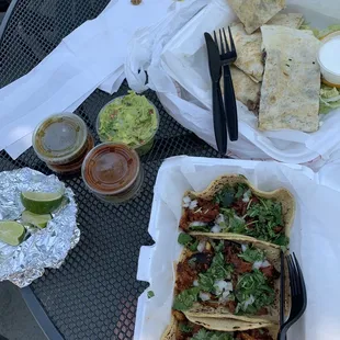 a table full of tacos, chips, salsa, and guacamole