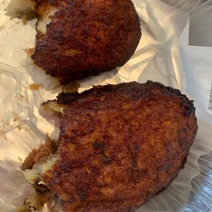two pieces of fried chicken on a piece of tin foil