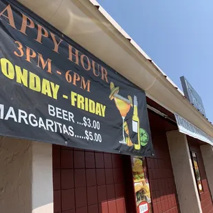 a happy hour sign on a building