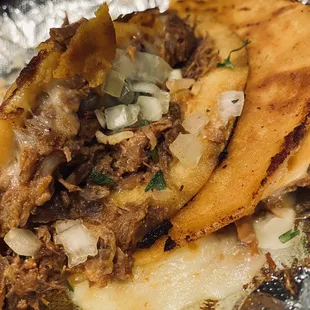 a close up of a taco with meat and onions