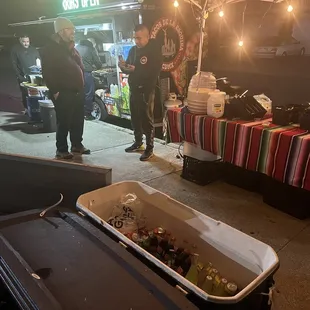 two people standing under a tent at a food stand