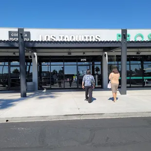 two people walking in front of a restaurant